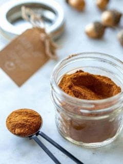 Jar and spoonful of apple pie spice next to a gift tag