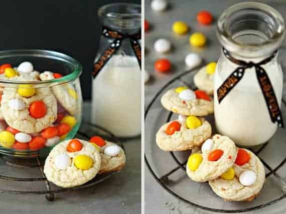 Cake mix cookies with candy corn m&m's on a round cooling rack next to a glass of milk