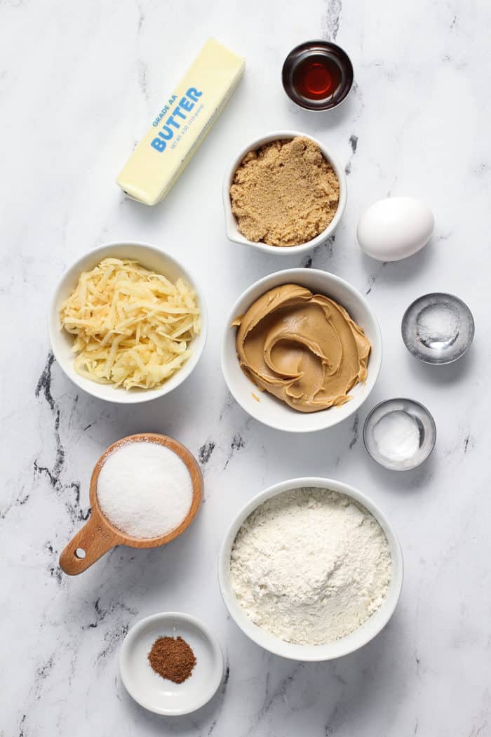 Ingredients for apple peanut butter cookies arranged on a marble countertop