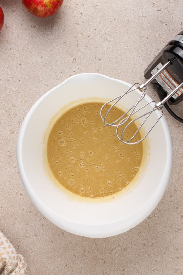 Wet ingredients for apple cider donut muffins mixed in a white bowl.