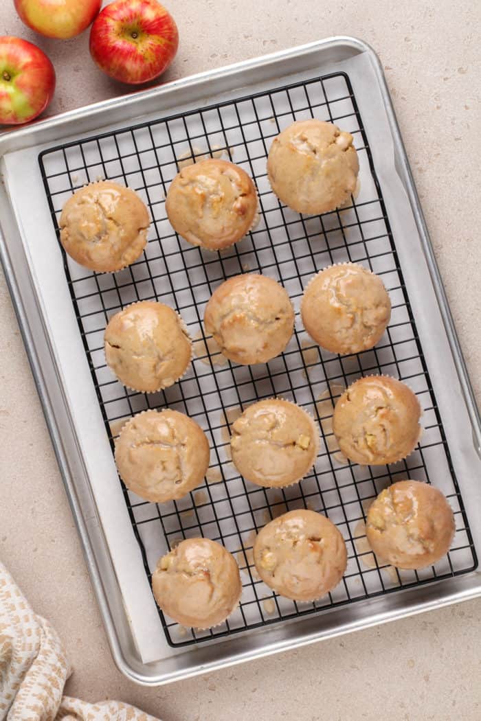 Freshly glazed apple cider donut muffins resting on a wire rack.