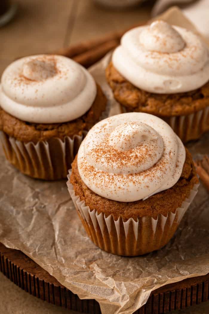 Three pumpkin spice cupcakes set on a piece of parchment paper