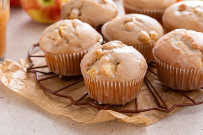 Several apple cider donut muffins set on a round wire rack.