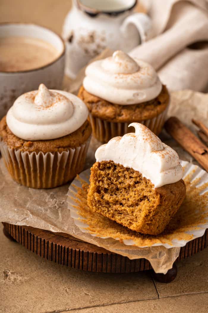 Three pumpkin spice cupcakes, one with a bite taken out of it