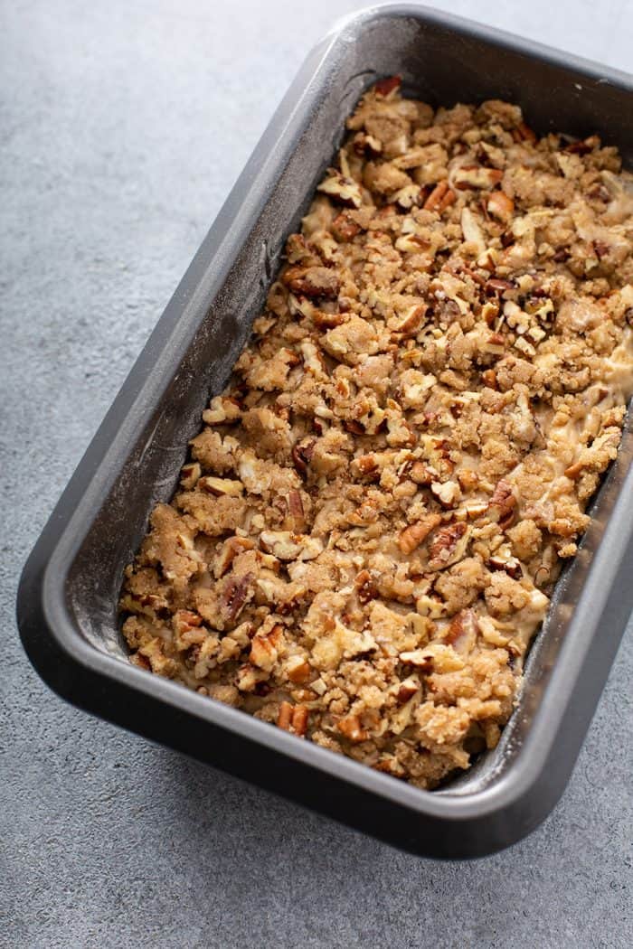 Apple pie bread topped with streusel in a loaf pan, ready to be baked