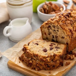 Sliced loaf of apple pie bread on a cutting board with coffee and creamer in the background