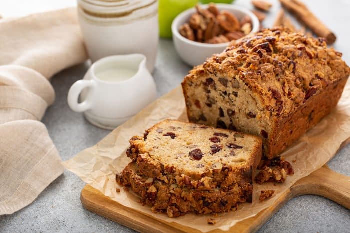 Sliced loaf of apple pie bread on a cutting board with coffee and creamer in the background