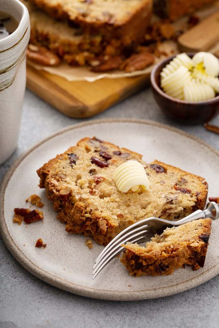 Fork cutting into a slice of apple pie bread on a cream plate