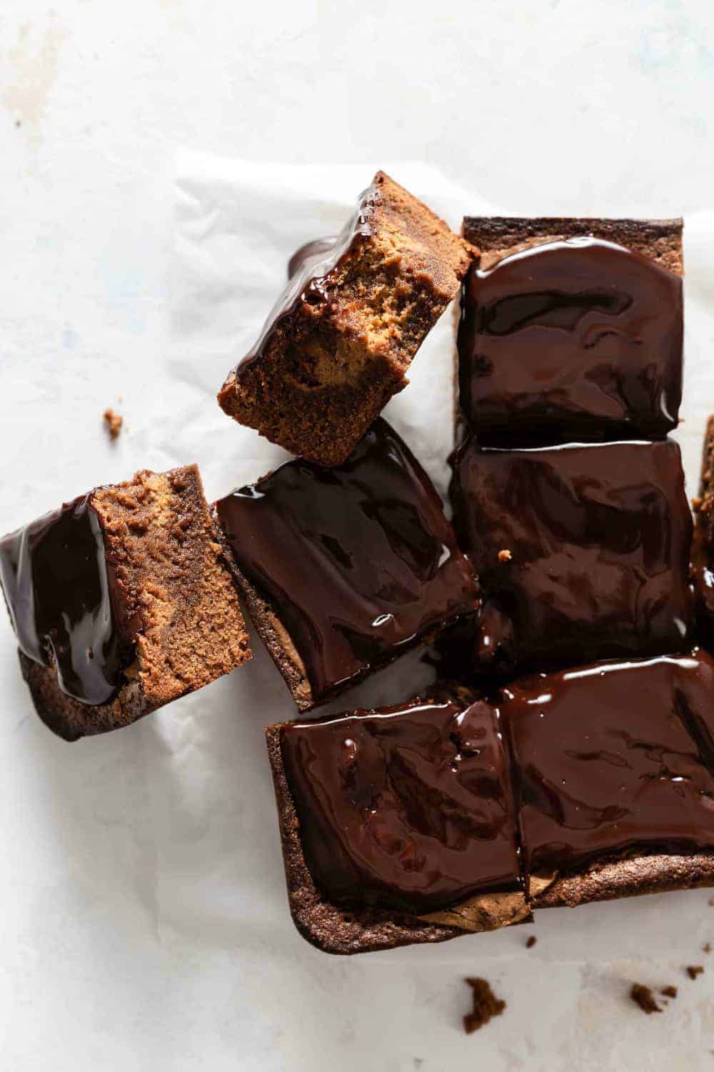 Sliced pumpkin blondies topped with chocolate ganache, with two turned on the side to show pumpkin swirl