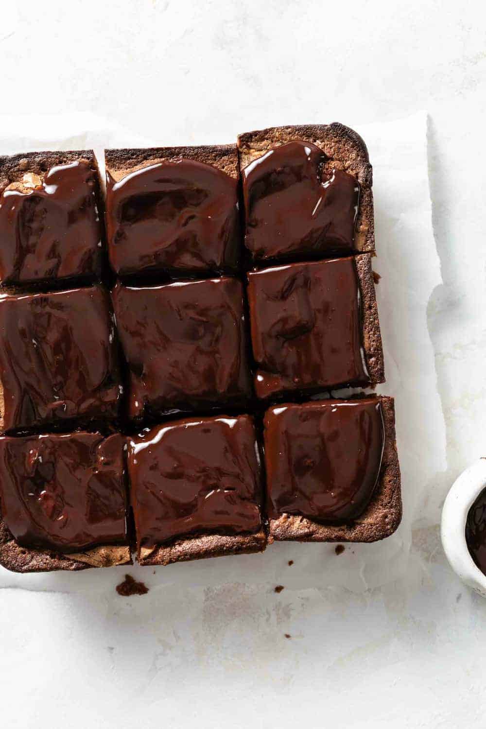 Sliced pumpkin brownies topped with chocolate ganache on a piece of parchment