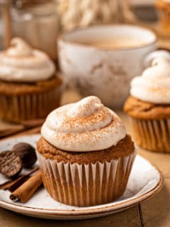 Pumpkin spice cupcake on a white plate, with more cupcakes in the background