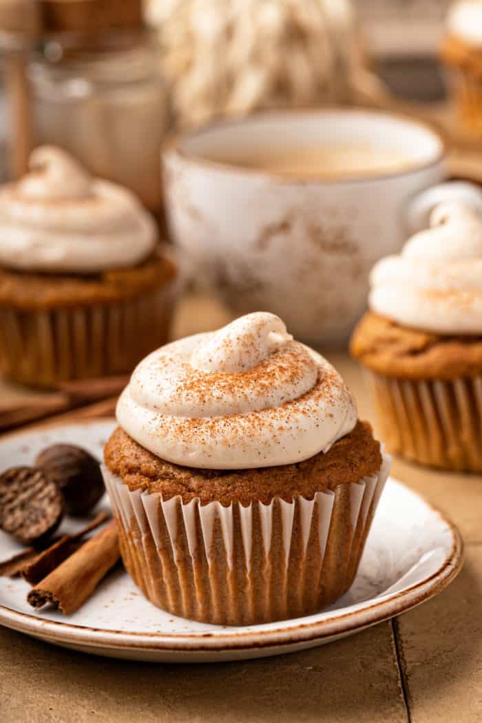 Pumpkin spice cupcake on a white plate, with more cupcakes in the background