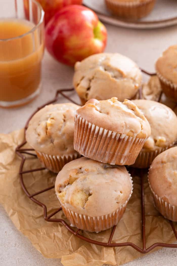 Glazed apple cider donut muffins arranged on a wire rack.