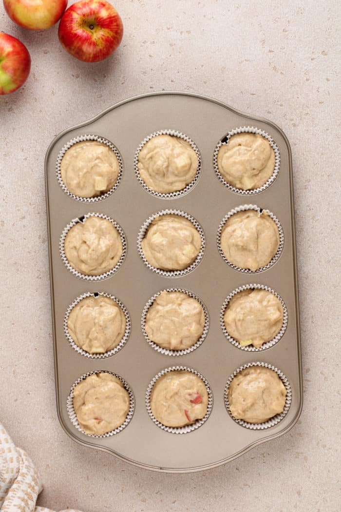 Apple cider donut muffin batter in a muffin tin, ready to go in the oven.