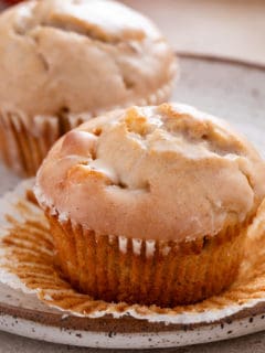 Close up image of an unwrapped apple cider donut muffin on a plate.
