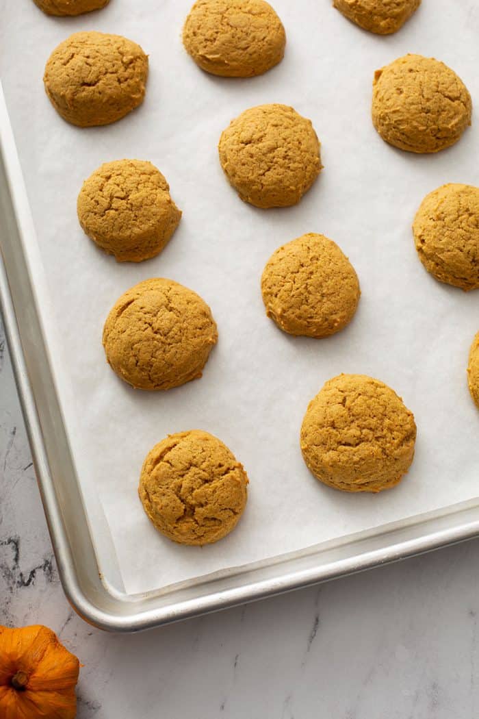 Baked pumpkin cookies on a parchment-lined cookie sheet