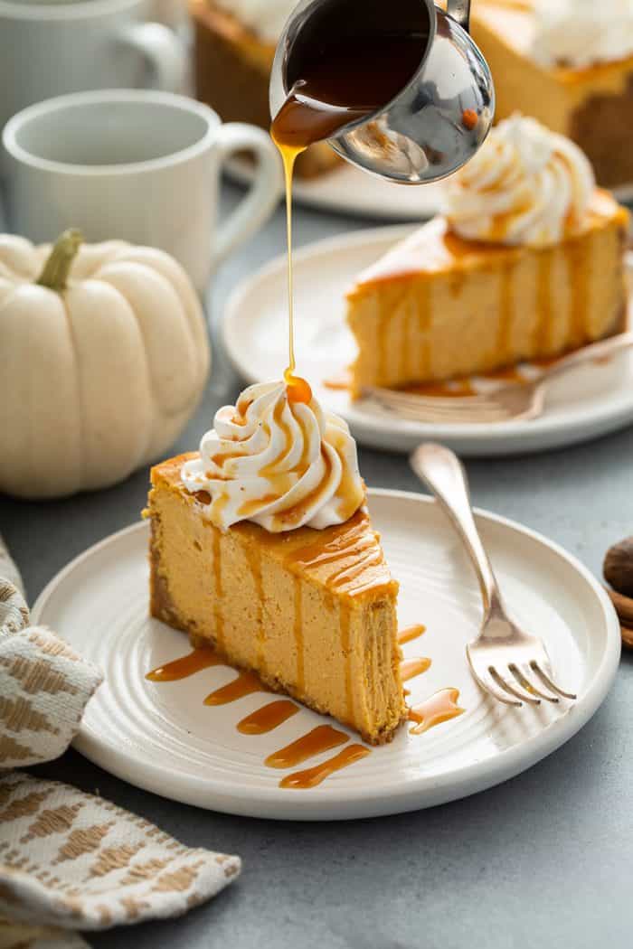 Caramel sauce being drizzled over a slice of pumpkin cheesecake