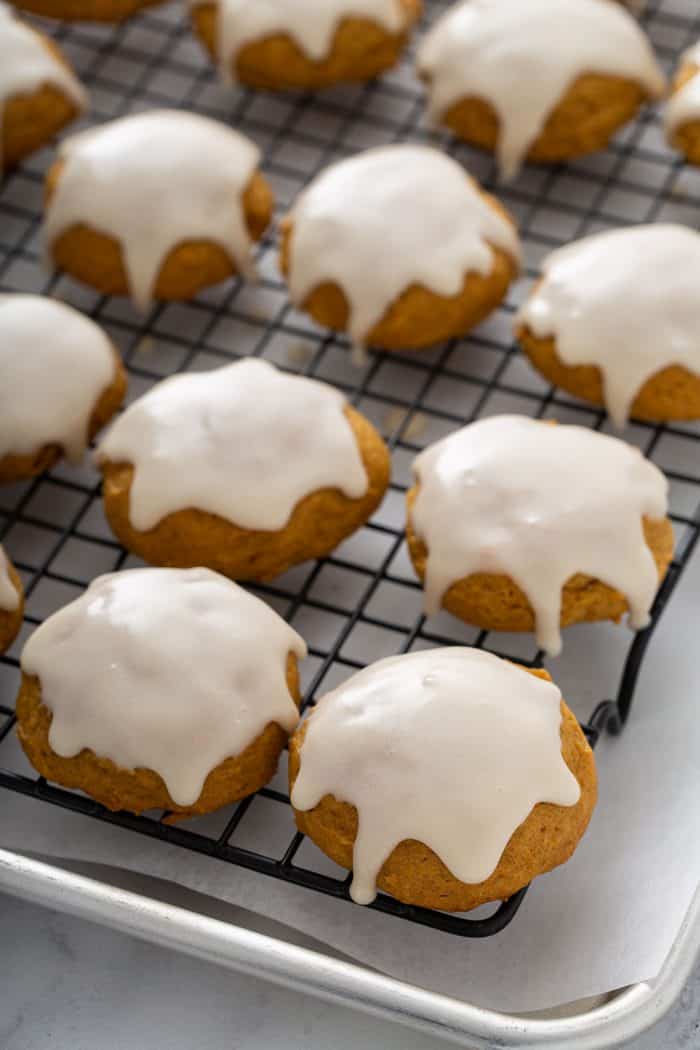 Iced pumpkin cookies lined on a cooling rack