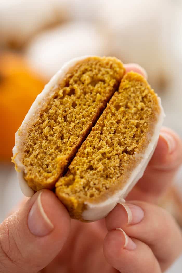 Hand holding a cut-open pumpkin cookie to show the texture inside