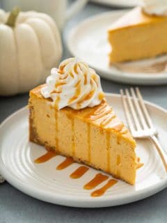 Slice of pumpkin cheesecake next to a fork on a plate