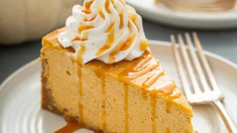 Slice of pumpkin cheesecake next to a fork on a plate