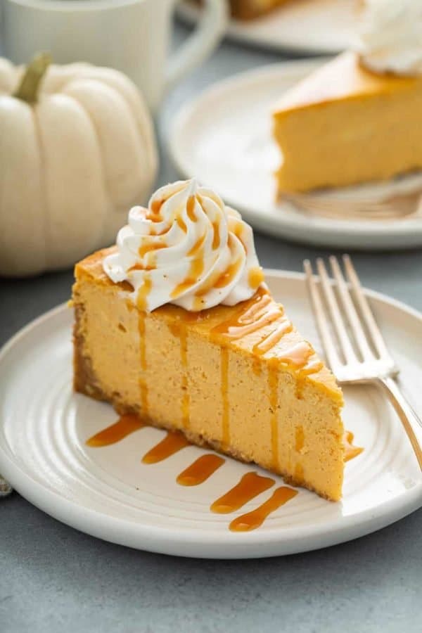 Slice of pumpkin cheesecake next to a fork on a plate