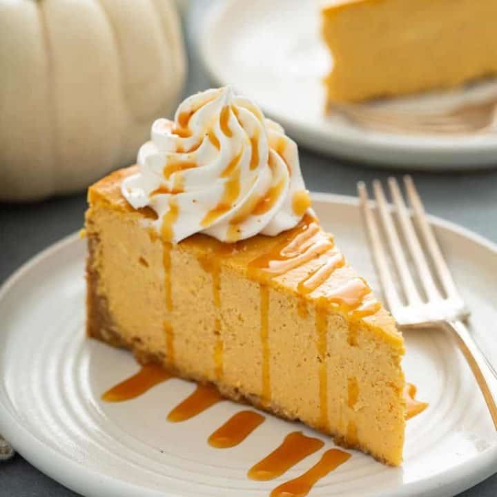 Slice of pumpkin cheesecake next to a fork on a plate