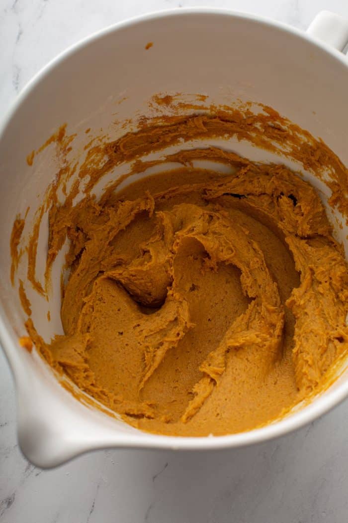 Pumpkin cookie batter in a white mixing bowl