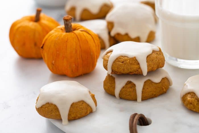 Iced pumpkin cookies arranged on a marble platter