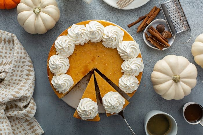 Overhead view of a sliced pumpkin cheesecake topped with whipped cream