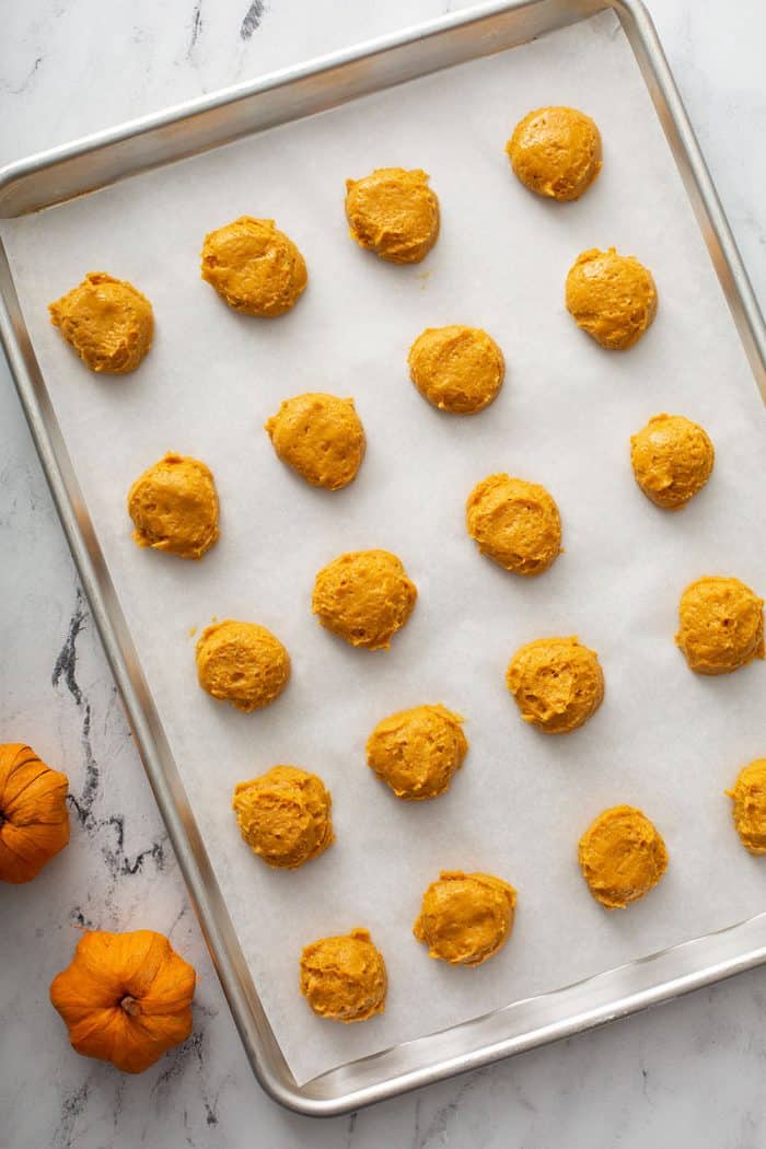 Pumpkin cookie dough portioned onto a parchment-lined cookie sheet