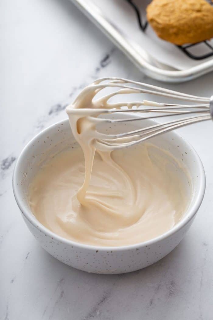 Whisk stirring together vanilla glaze icing in a white bowl