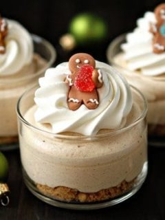Individual gingerbread cheesecakes topped with whipped cream and tiny gingerbread man cookies