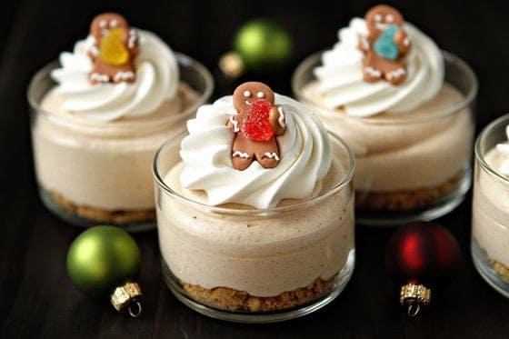 Individual gingerbread cheesecakes topped with whipped cream and tiny gingerbread man cookies