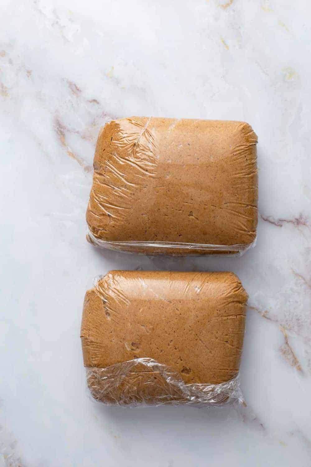 Dough for pumpkin molasses cookies wrapped in plastic wrap on a countertop