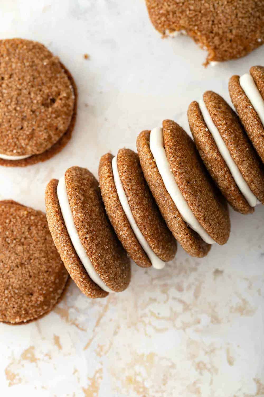 Pumpkin Molasses Sandwich Cookies arranged on a countertop, lined end-to-end on their sides