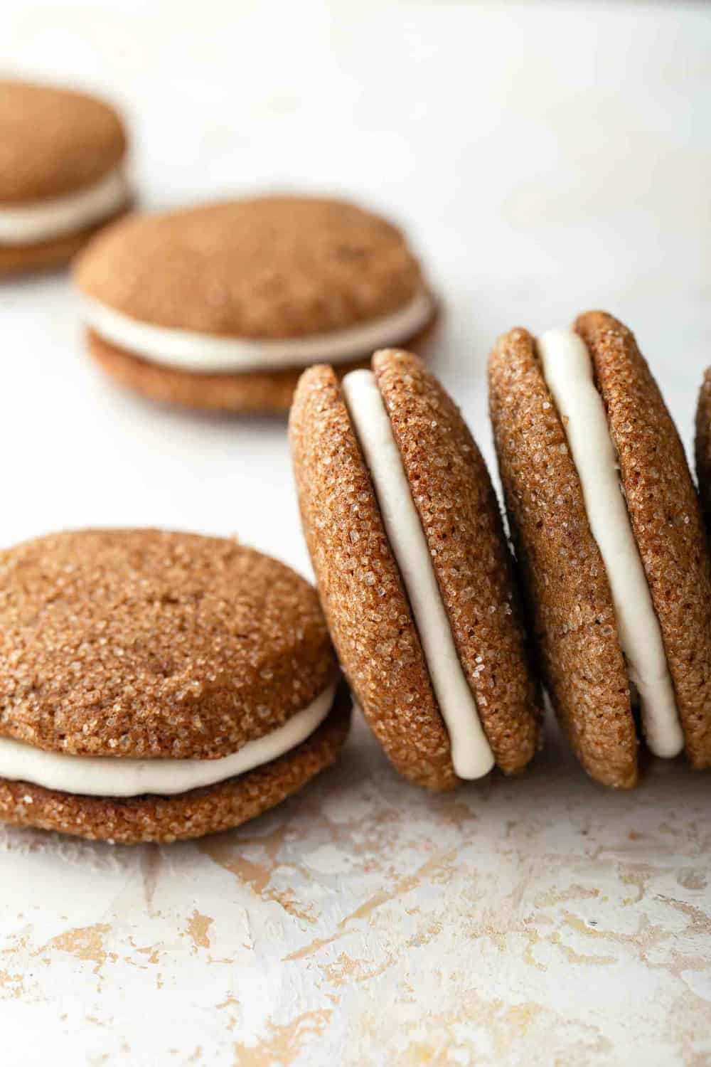 Pumpkin molasses sandwich cookies arranged on a countertop, some propped on their sides