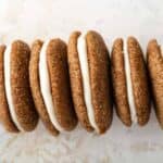 Line of pumpkin molasses sandwich cookies propped on their sides on a countertop