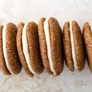Line of pumpkin molasses sandwich cookies propped on their sides on a countertop