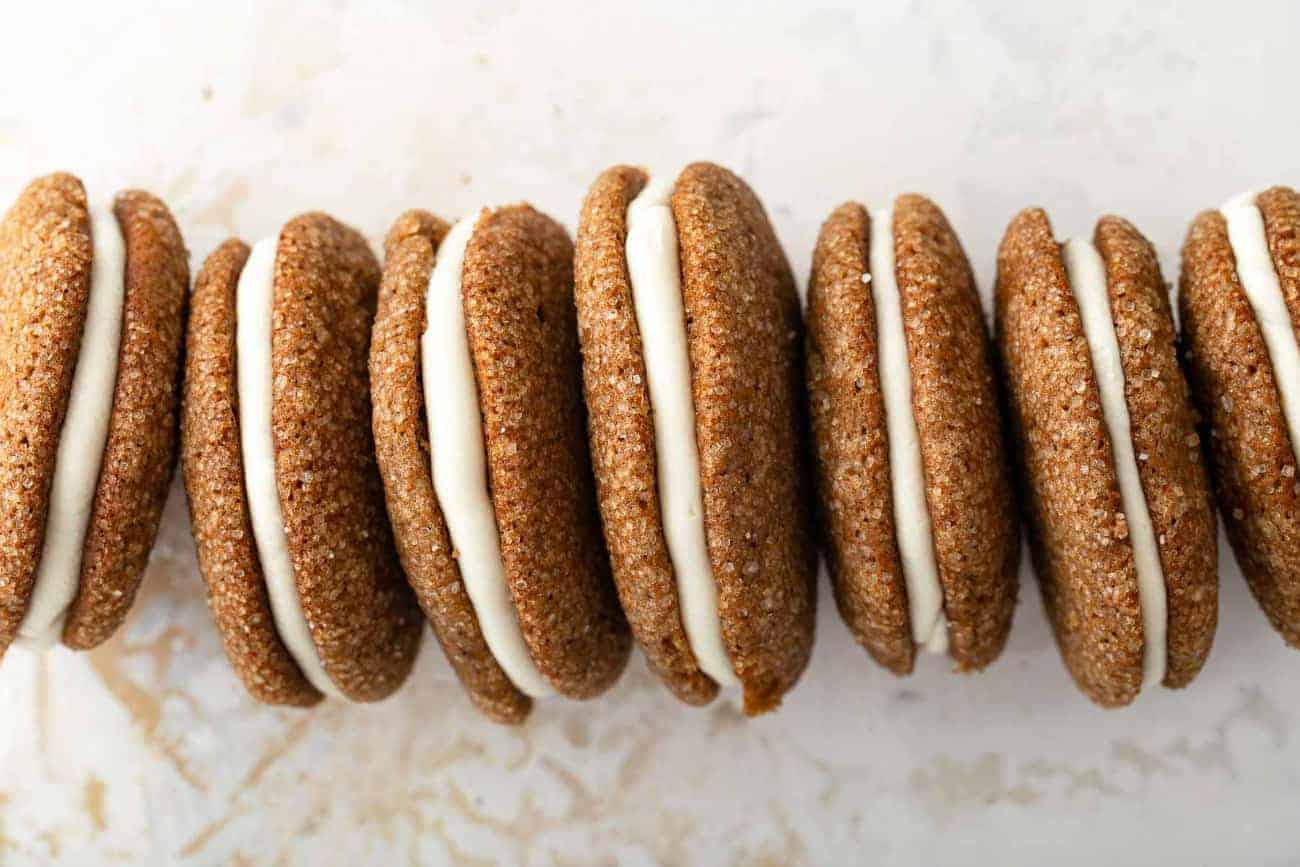 Line of pumpkin molasses sandwich cookies propped on their sides on a countertop