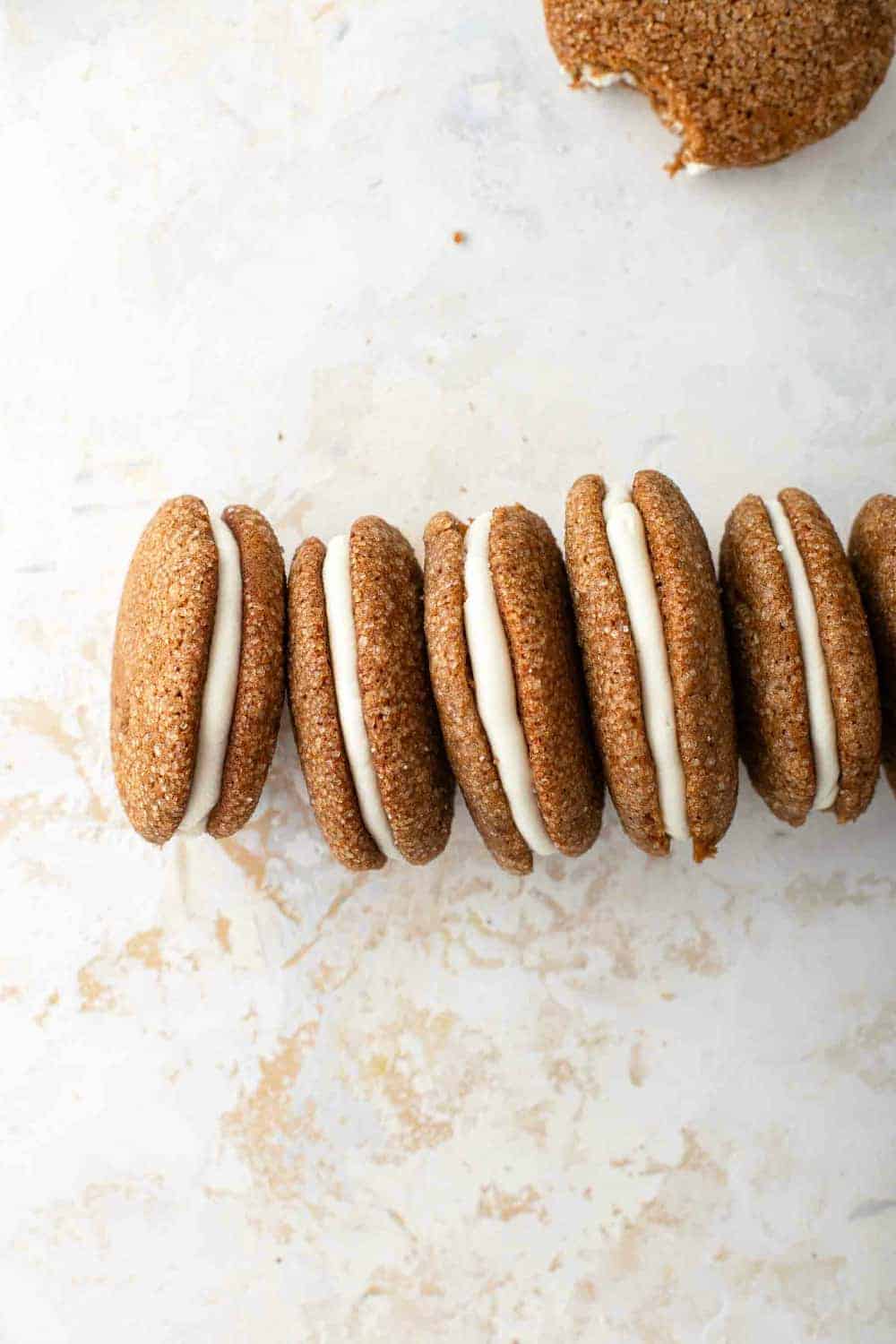 Pumpkin molasses sandwich cookies lined up on their sides on a countertop