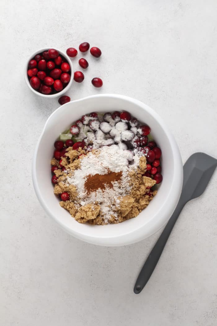 Ingredients for cranberry apple crisp filling in a white mixing bowl.