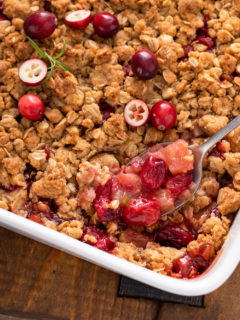Spoon picking up a serving of cranberry apple crisp from the baking dish.