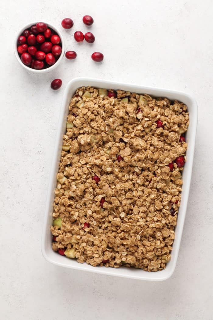 Assembled, unbaked cranberry apple crisp in a white baking dish, ready to go in the oven.