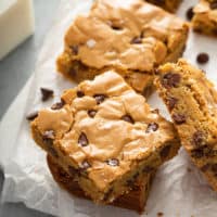 Stacked chocolate chip blondies on a piece of parchment paper