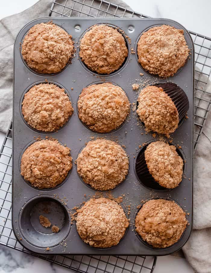 Overhead view of banana crumb muffins in a muffin tin, set on a dish towel