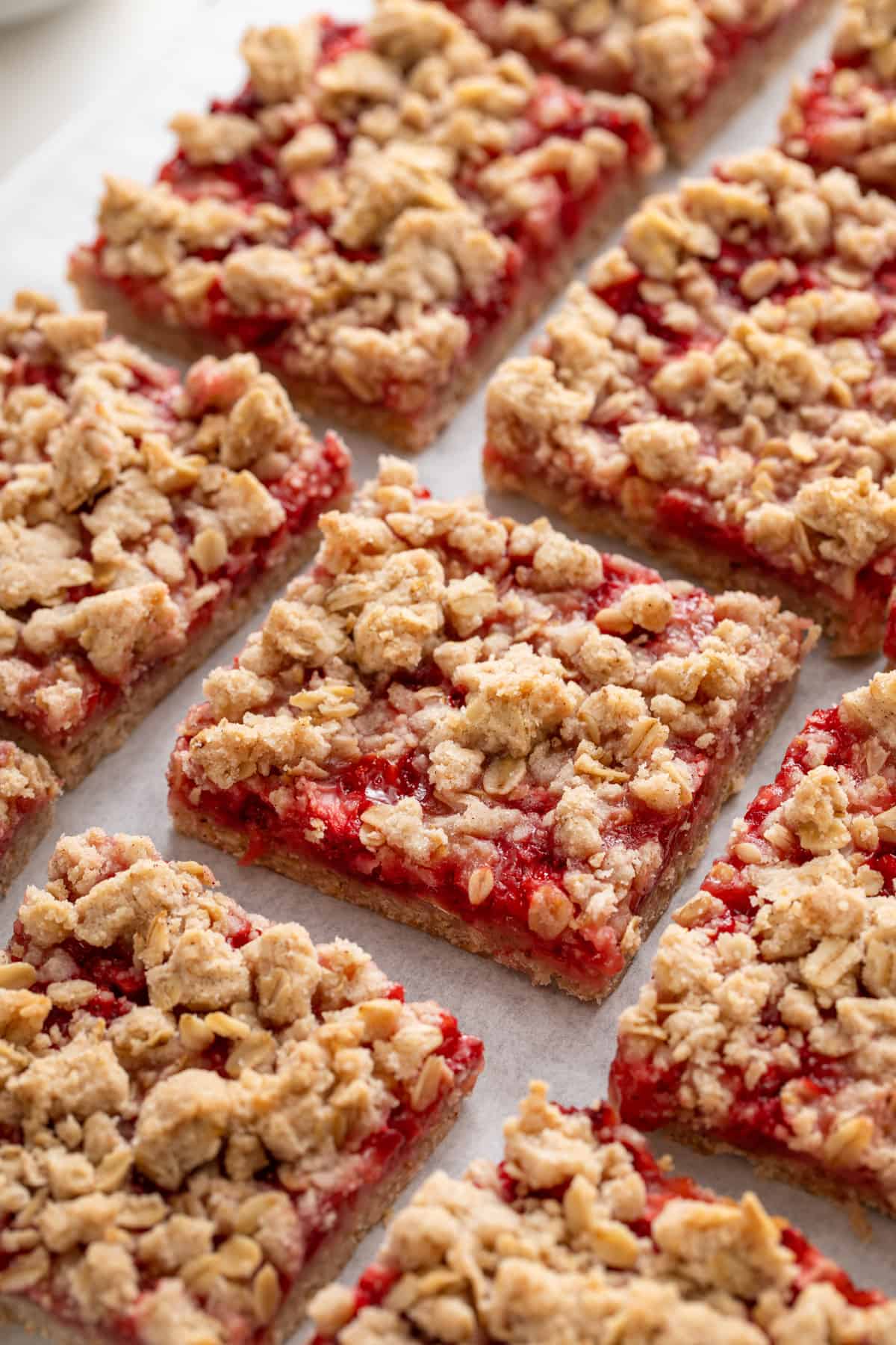 Close up view of sliced strawberry oatmeal bars on a piece of parchment paper.