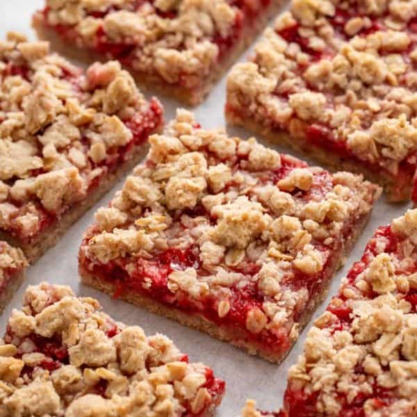 Close up view of sliced strawberry oatmeal bars on a piece of parchment paper.