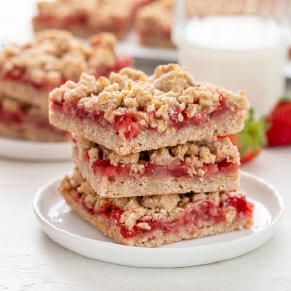 Strawberry oatmeal bars stacked on a white plate.