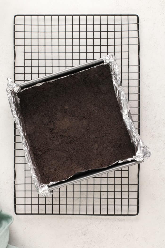 Oreo crust for cheesecake bars in a foil-lined pan, ready to have the filling added.